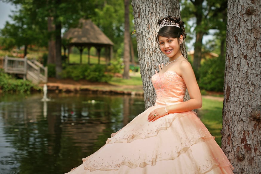 A 15 year old girl poses in her Quinceanera dress by a lake